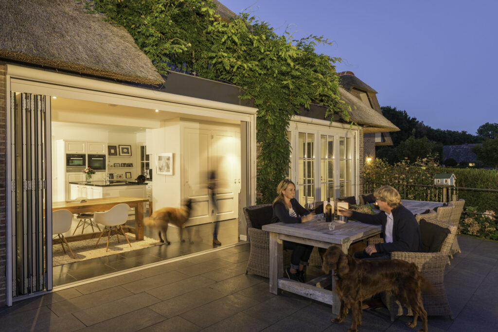 Abendstimmung - Die zwei integrierten Glas-Faltwände von Solarlux verbinden Terrasse und Wohnraum.